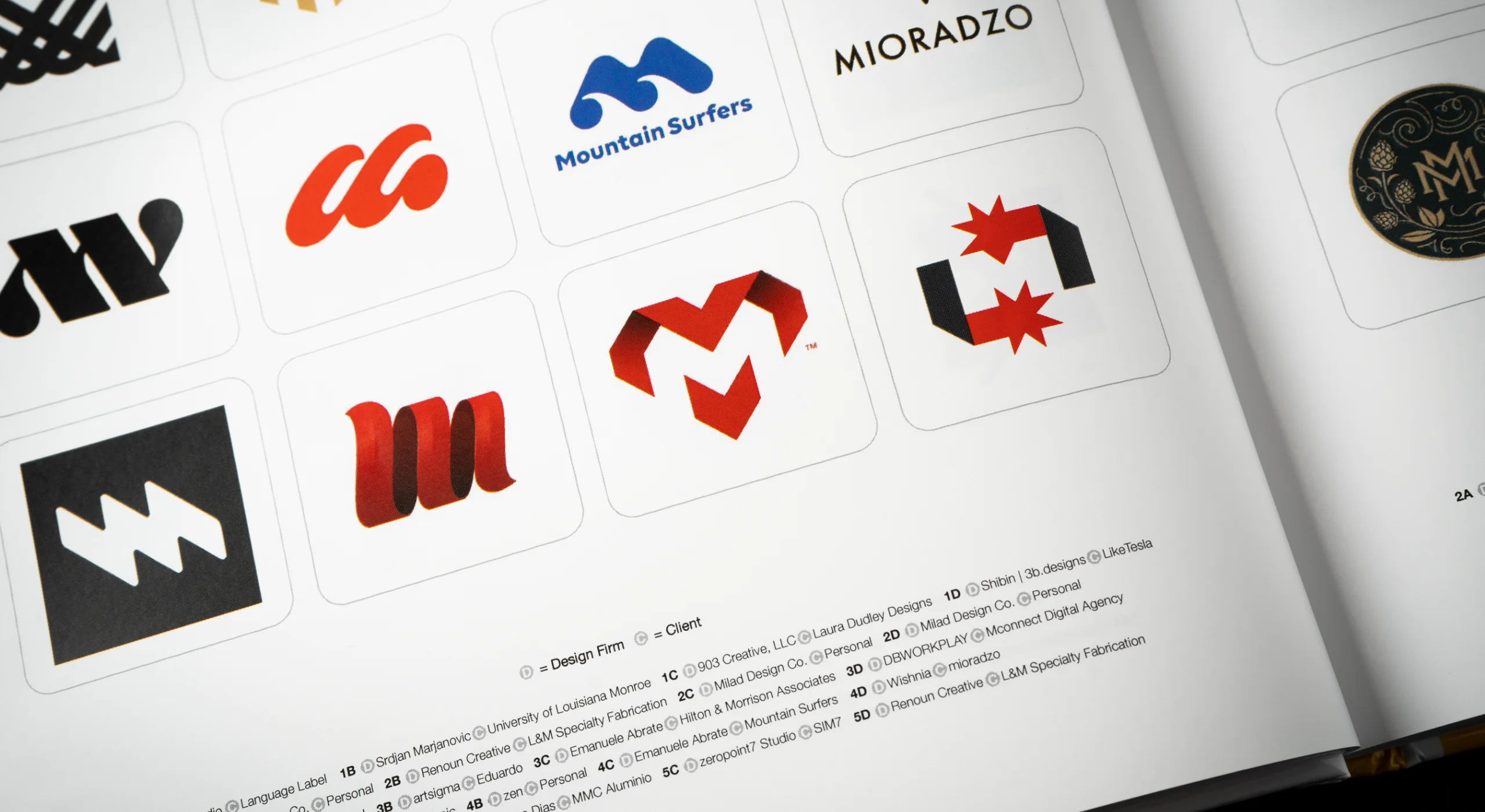 A photo of a book page showcasing a modern letter m logo design featured in the logolounge book