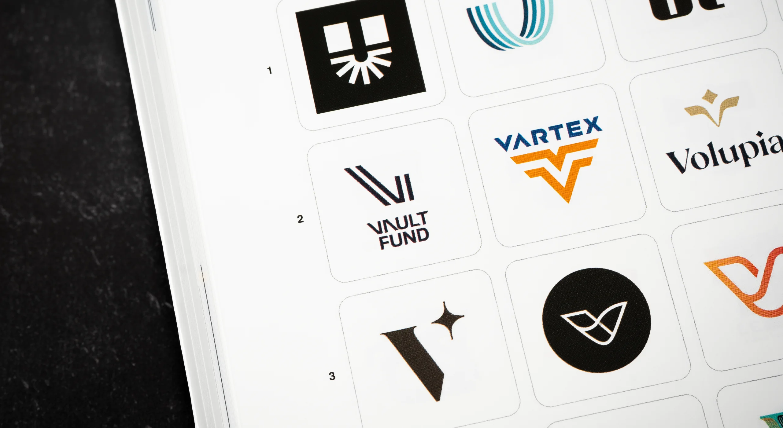 A photo of a book page showcasing an award-winning logo mark for Vault Fund - a new venture capital investment firm